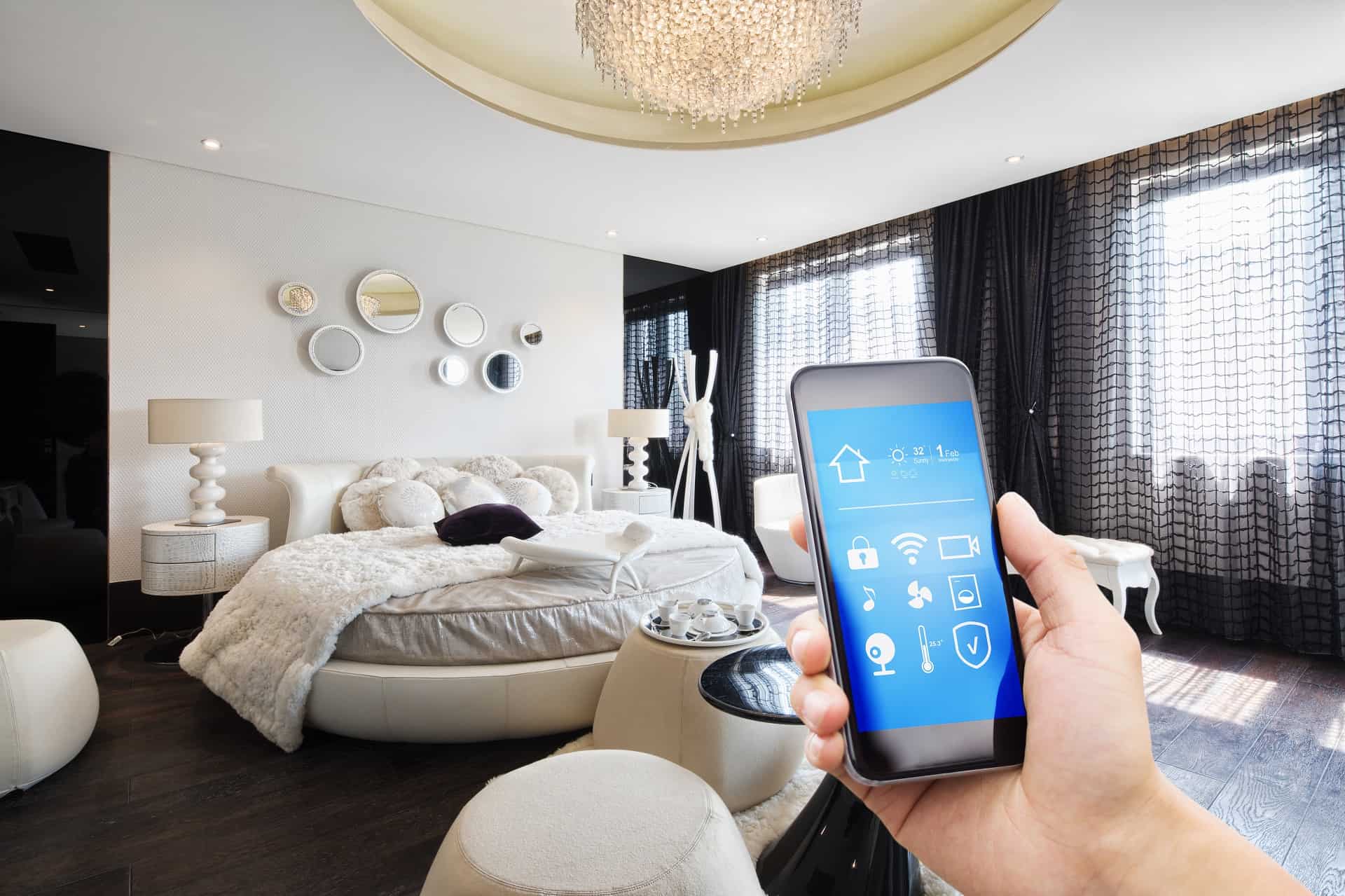 Smart phone with a smart home app in foreground, bedroom in the background.