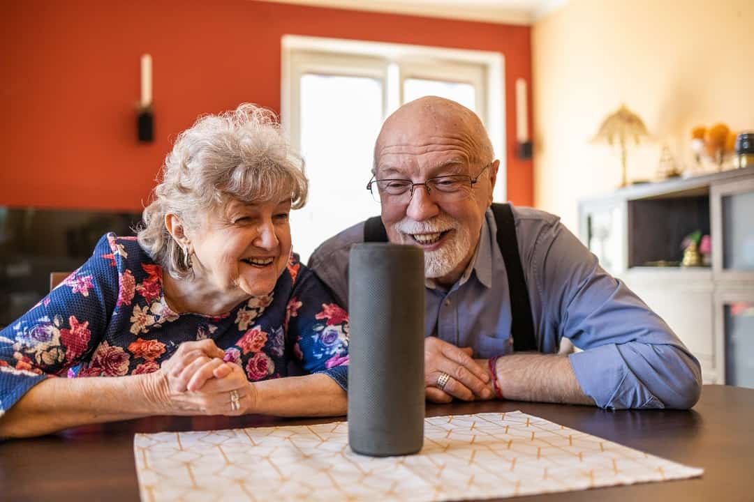 Elderly couple talking to a smart speaker.