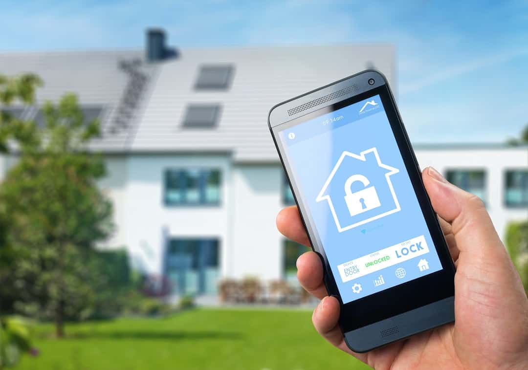Cell phone with an image of a house and a lock in the foreground with a house in the background.