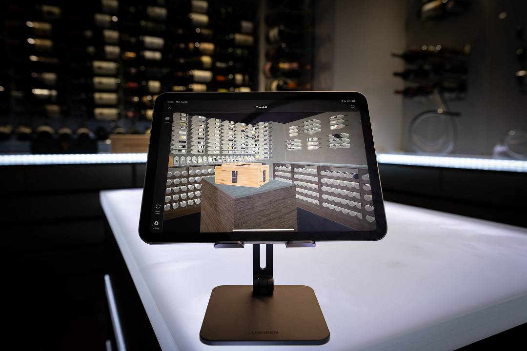 Tablet with InVintory's Opus app rendering a wine cellar, picture of wine cellar in the background.