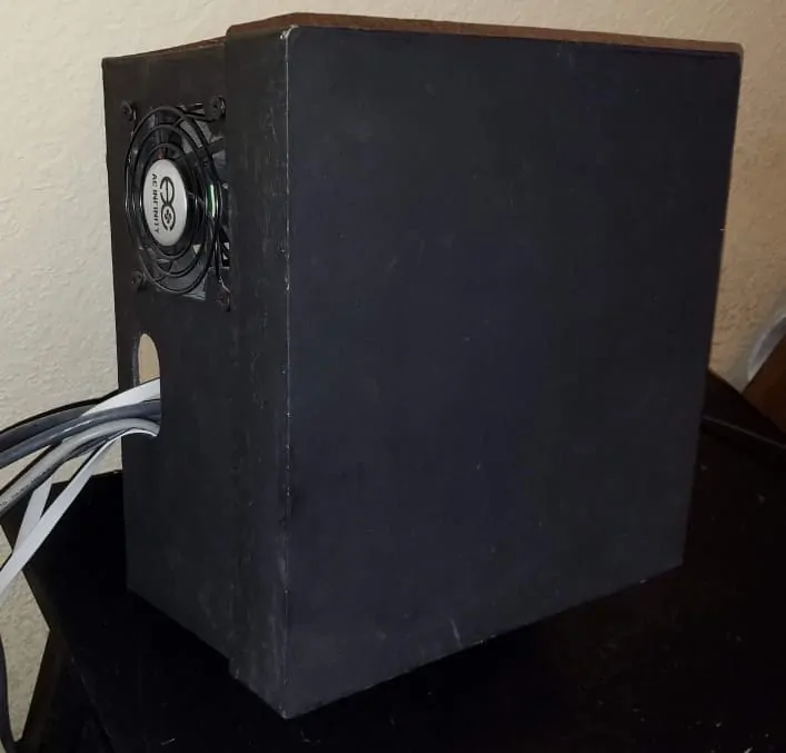 Black paperboard box with a fan and network cables going into it.