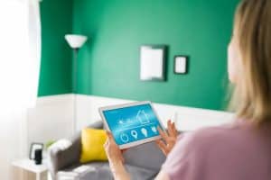 Woman using an app on the tablet to turn on her lights with a smart device