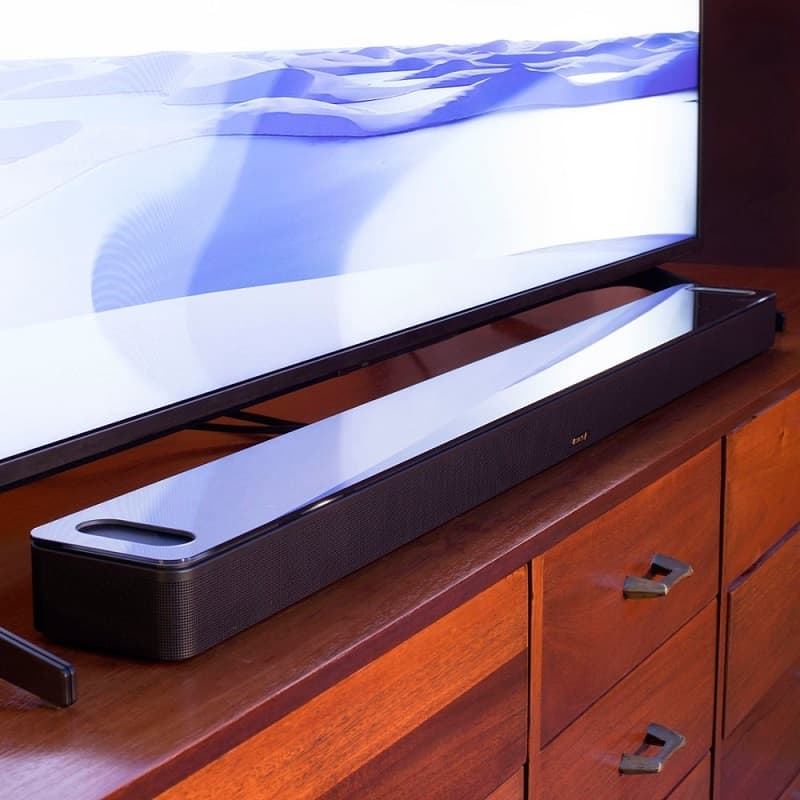 Bose - Smart Soundbar 900 With Dolby Atmos and Voice Assistant on a TV console and below a TV