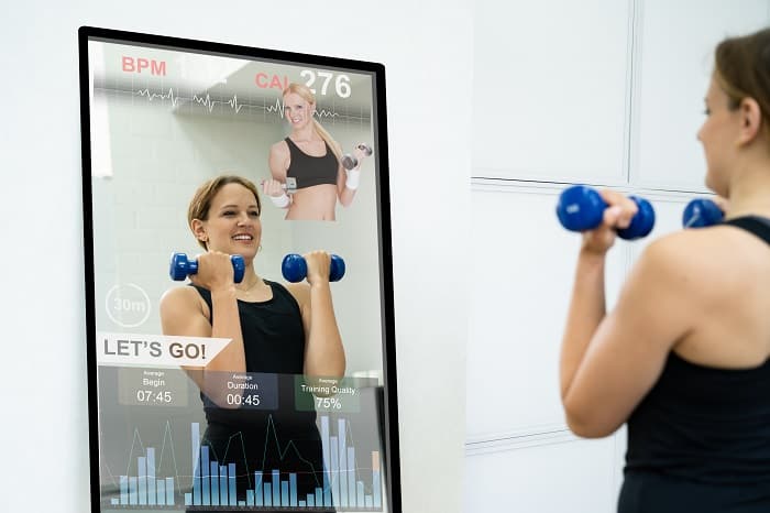 Woman working out in front of a smart mirror.