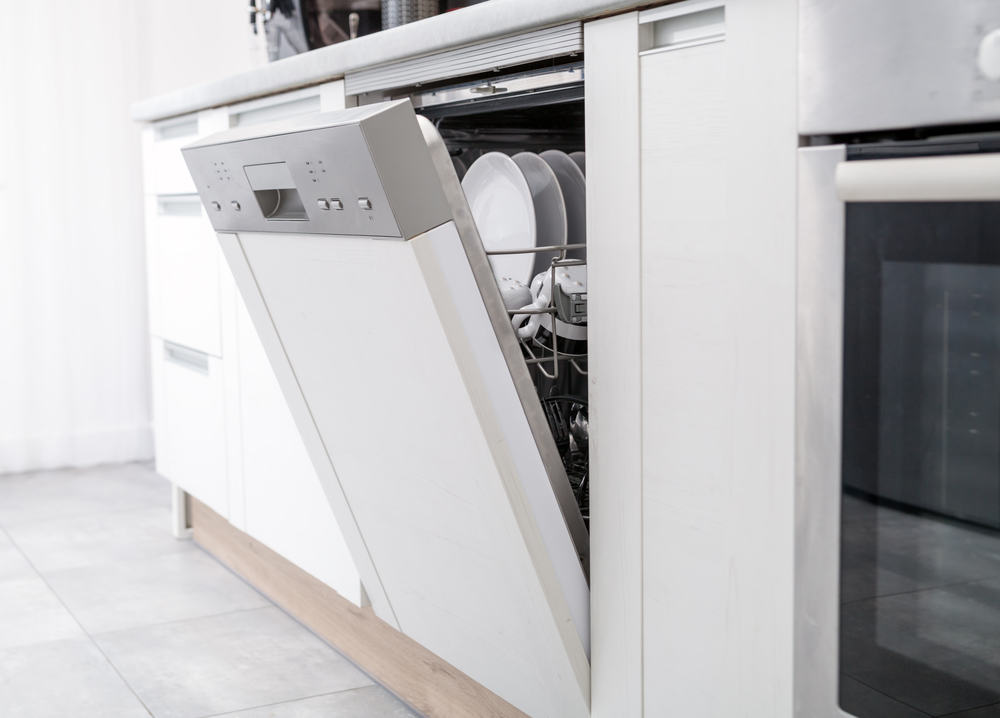 Open dishwasher with clean dishes in the white kitchen