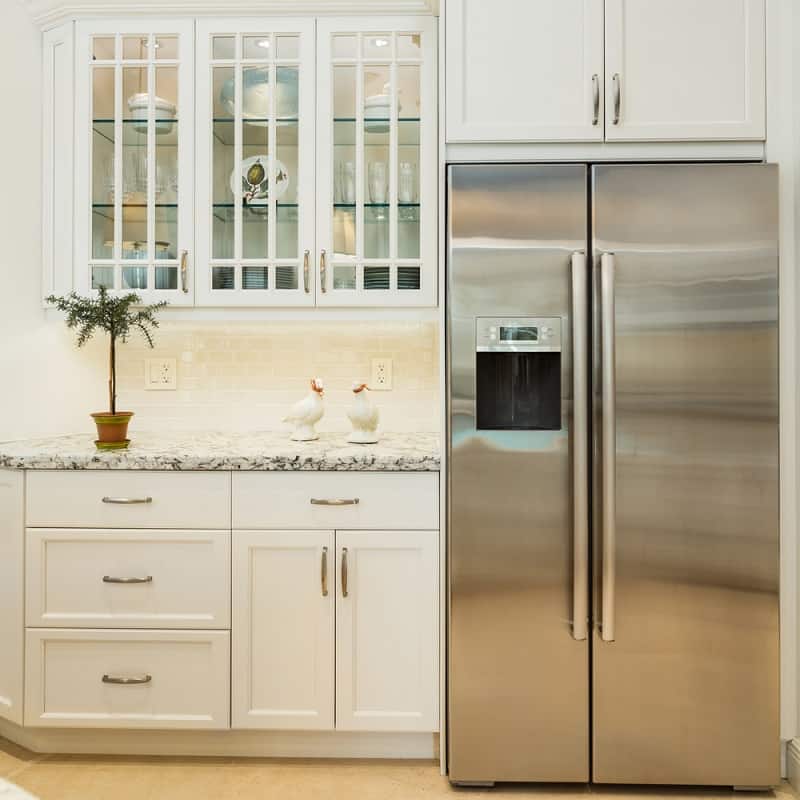 White kitchen with a stainless steel refrigerator.