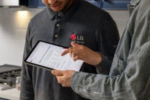 LG service rep and customer looking at documents on a tablet.