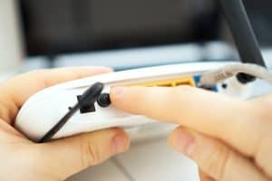 Person holding the reset button on a router.