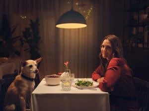 Drew Barrymore and a dog at a dinning table.