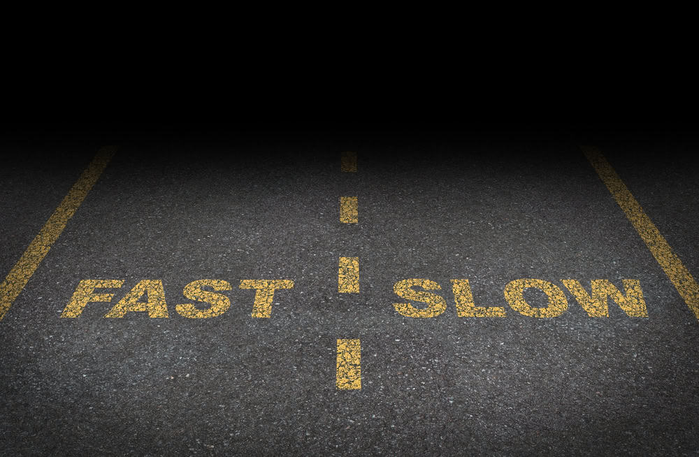 Black street in the dark with two lanes, one marked fast and the other slow.