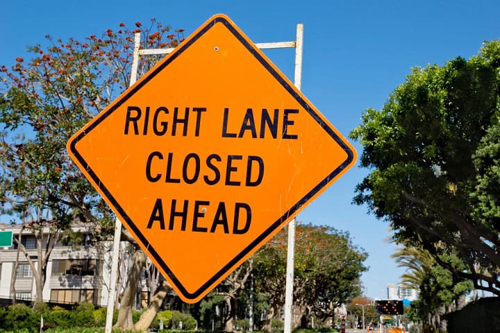 Orange roadwork sign in a diamond shape with "Right Lane Closed Ahead" on it.