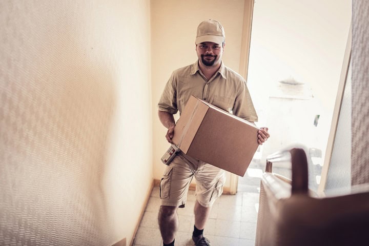 Delivery person carrying a package up some stairs.