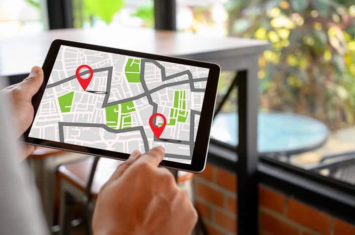 Person holding a tablet with a map and two waypoints displayed on it.