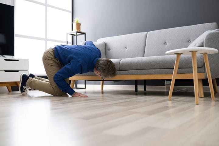 Man looking under the couch for a lost item.