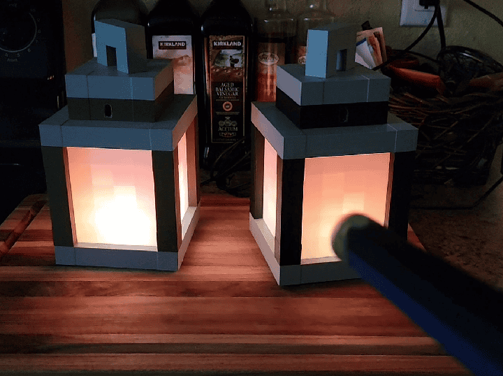 Magiquest wand pointed at two Minecraft style lanterns.