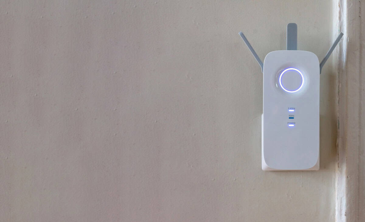 Wifi network extender on a beige wall.