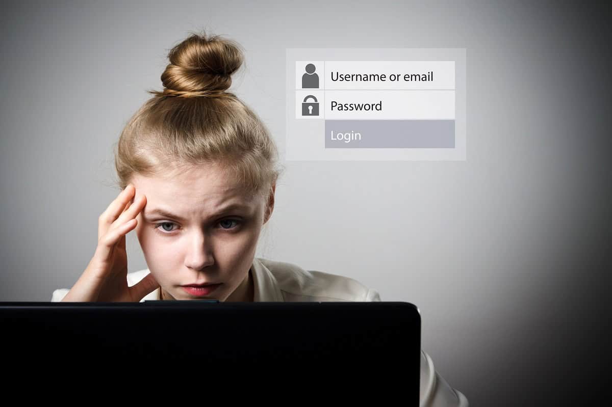 Woman staring at laptop screen and concentrating. Overlay of a computer login form next to the woman indicating that she's trying to remember her login information.
