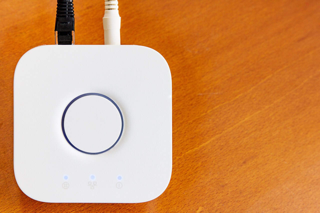 Smart home hub in white on a wooden desktop.