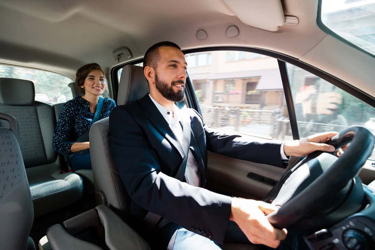 Similing taxi driver talking with female passenger. Rideshare, Uber